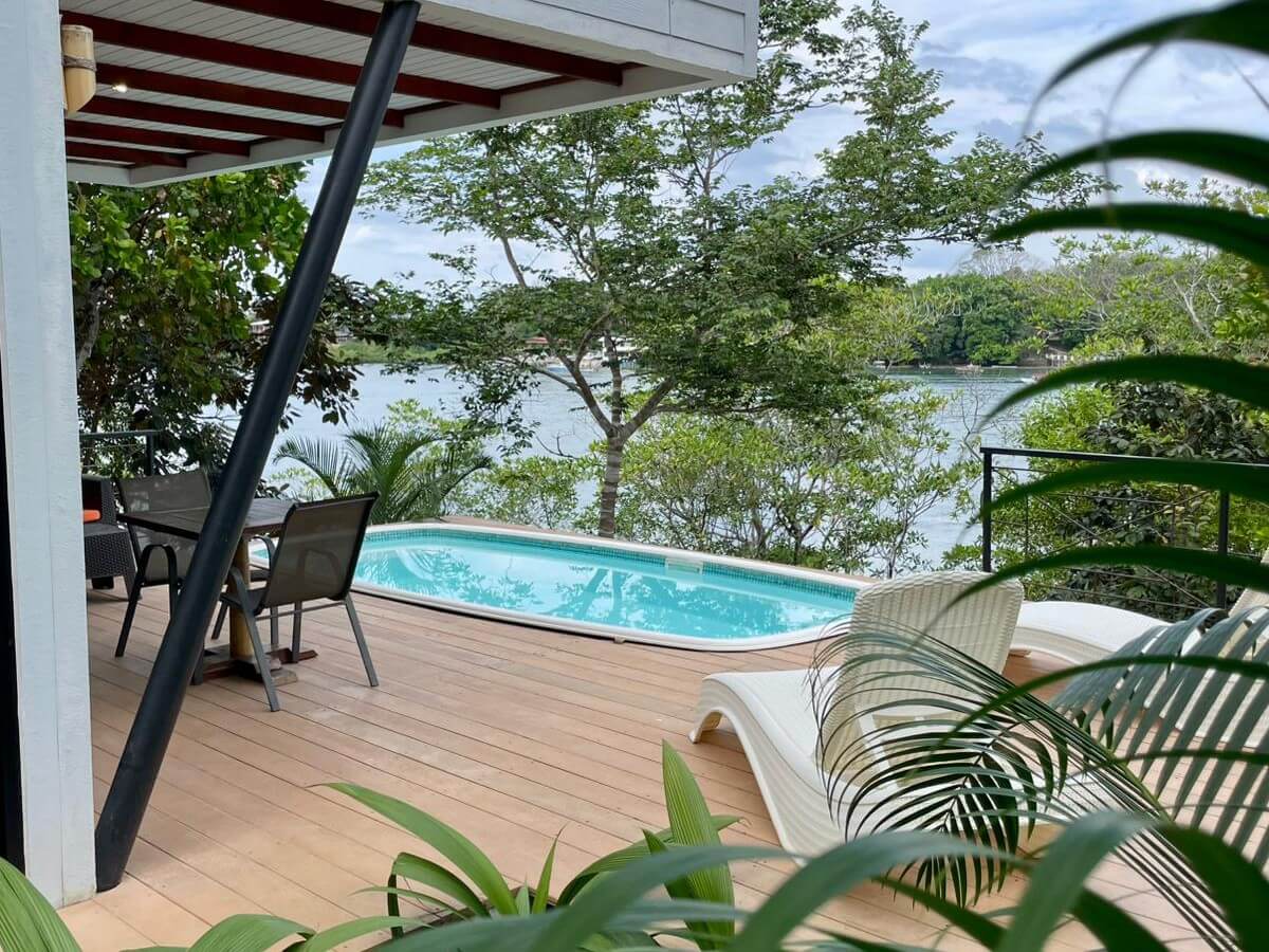 Terraza con piscina y vista al mar entre la vegetación